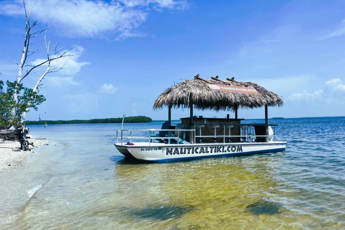 Nautical Tiki Cruises | Tiki boat pulled up on a beautiful island close to Fort Myers Beach