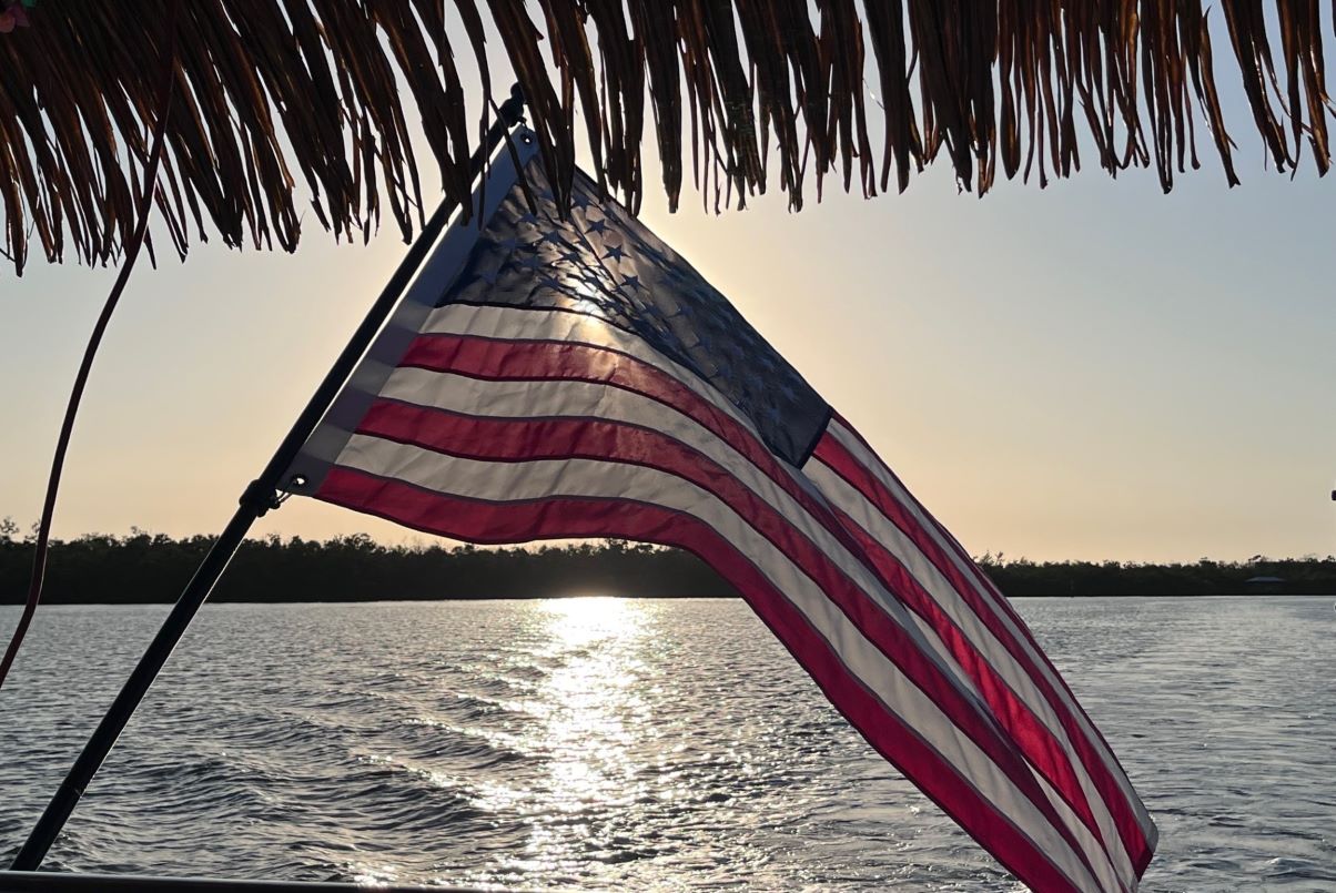 Nautical Tiki Cruises | Fort Myers Beach | The American flag on the back of a tiki boat as the sun is starting to set on the Gulf of Mexico.